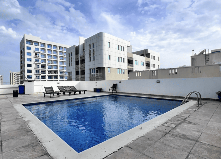 Rooftop swimming pool with lounge chairs in a spacious apartment for rent in Juffair.